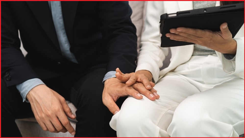 Man putting hand on woman's knee while she pushes hand away.