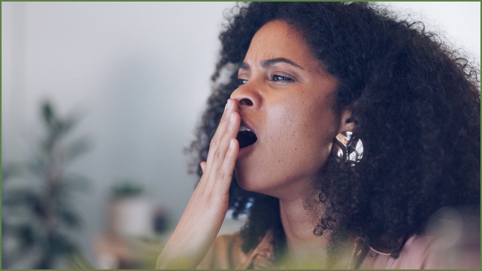 Woman yawning, holding her hand over her mouth.