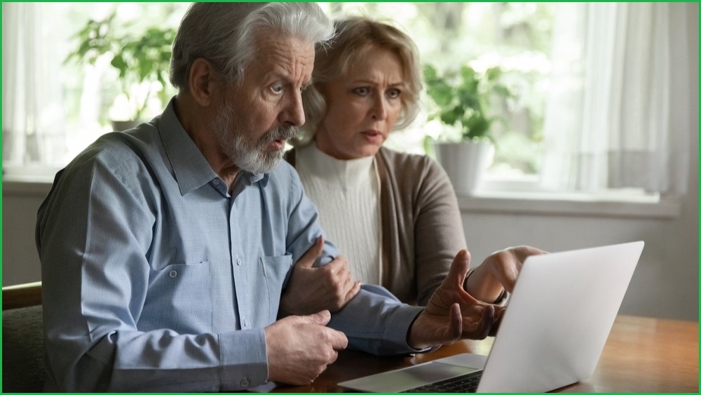 Older couple looking at a computer screen in shock.