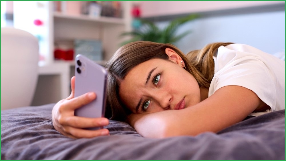 Depressed girl looking at her mobile phone