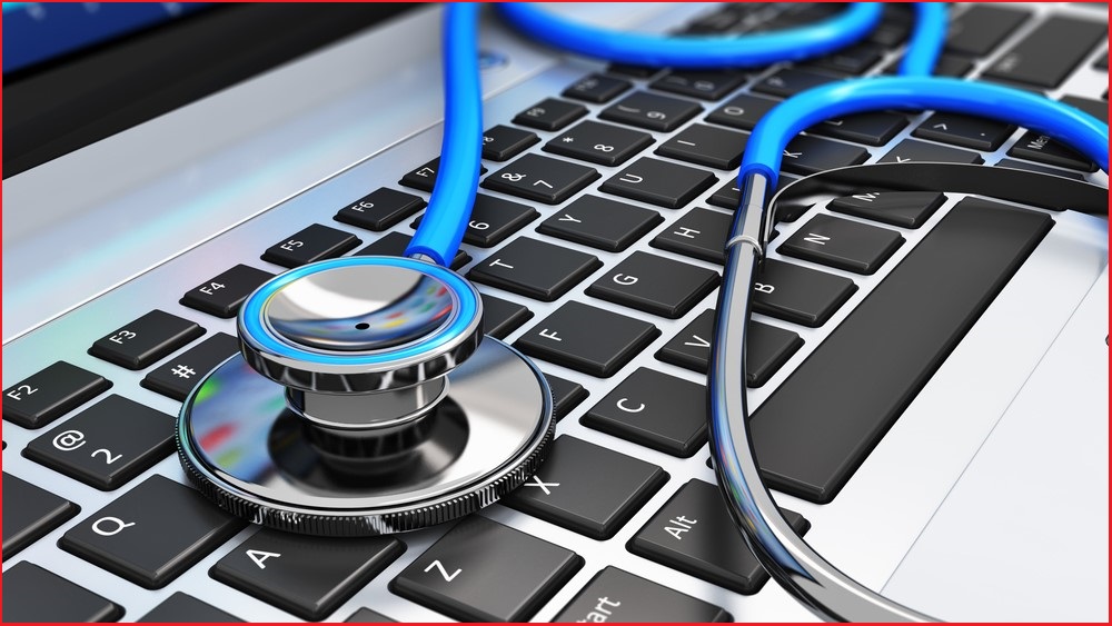 A close up of a stethoscope resting on the keyboard of a laptop.
