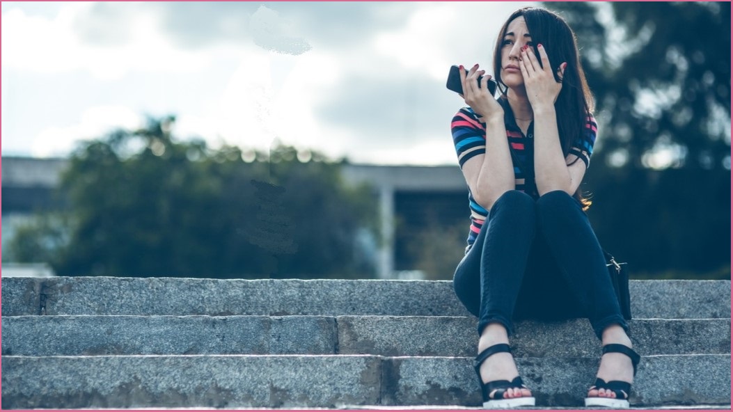 Young person sitting on stairs holding a phone