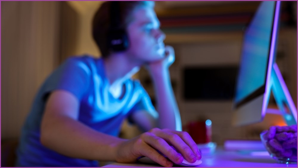 Teenage boy sitting at a computer.