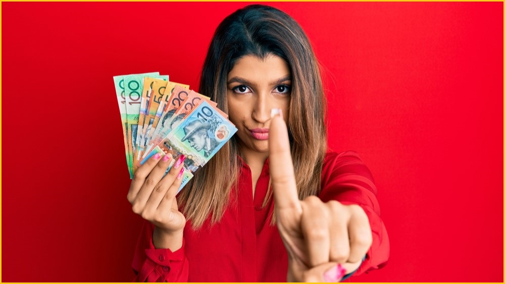Woman holding Australian dollars, waving her finger as if to say no
