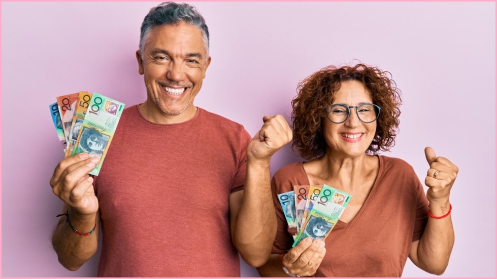 A man and woman hold up a celbratory fist and a handful of Aussie dollars.