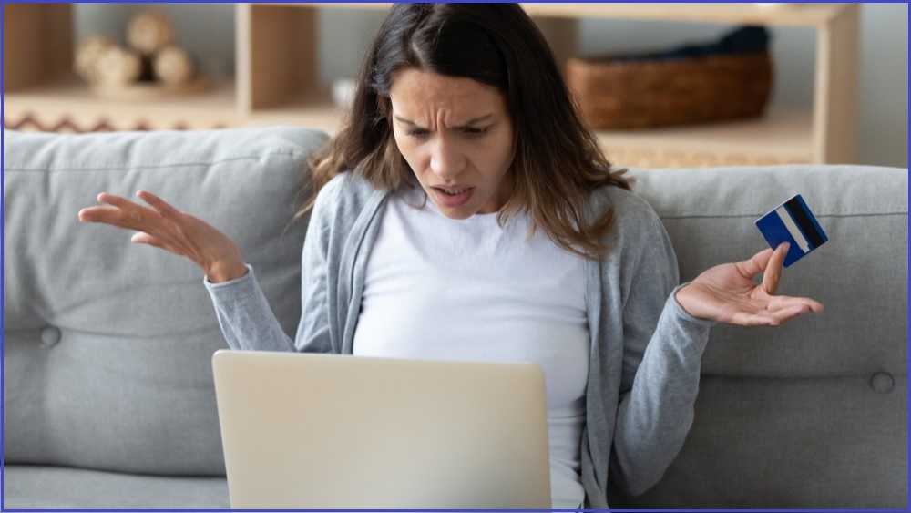 Shocked woman looking at a computer screen and holding a credit card