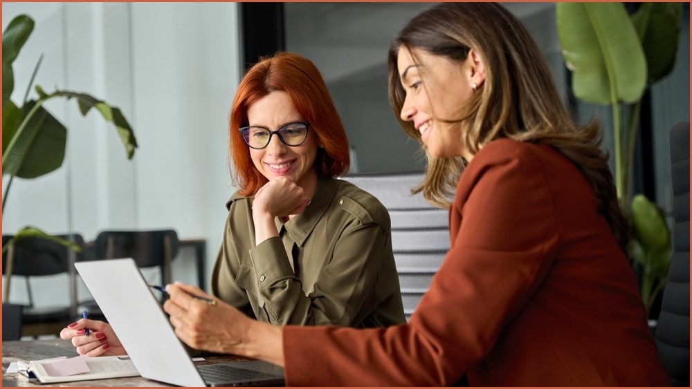 Two women looking at a computer screen smiling.