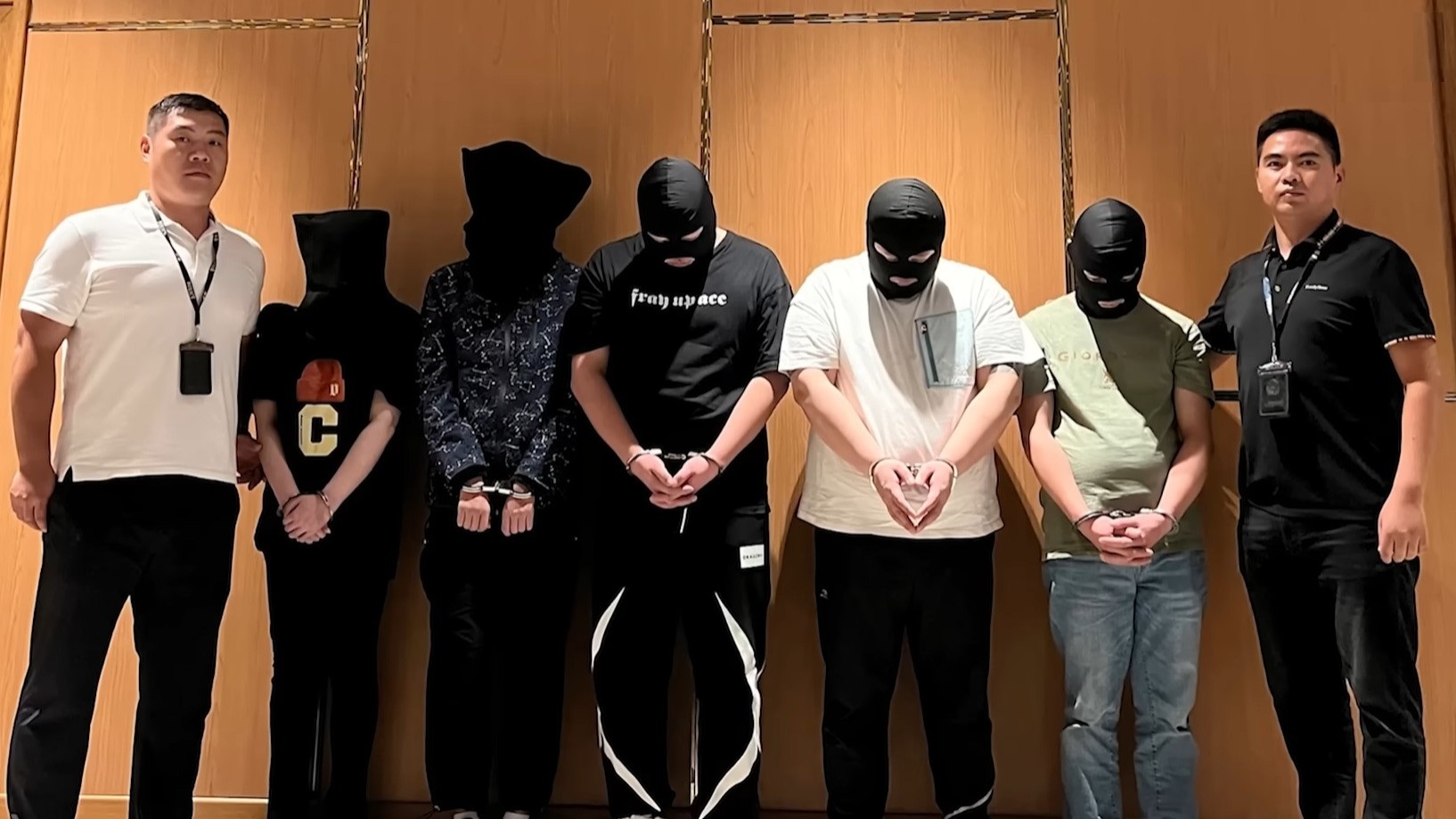 Five scammers lined up with two officials.