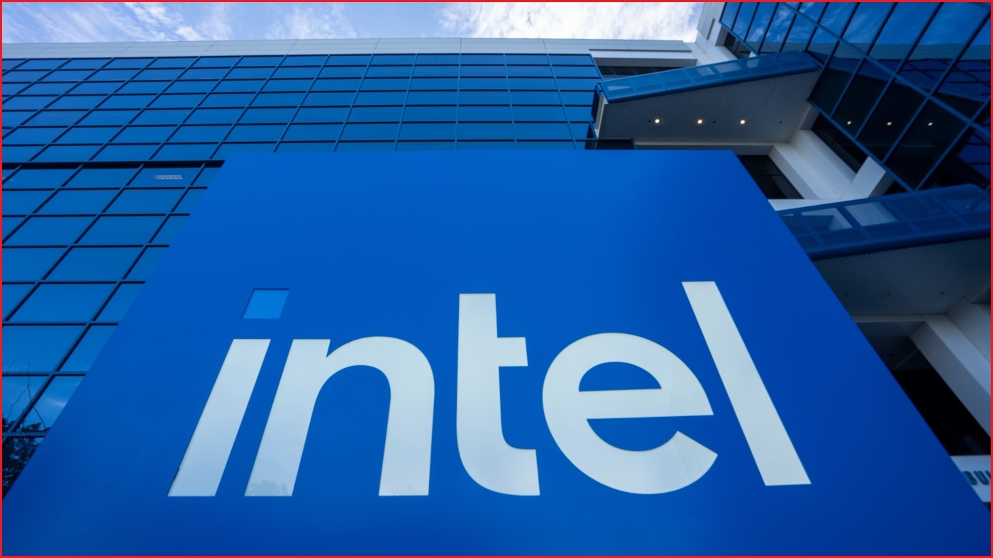 A close up of the Intel logo, looking upwards to the sky, in front of a large office building.
