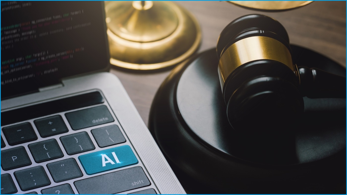 A close up of a laptop with 'AI' label on its Enter key. Next to the laptop is a legal gavel.