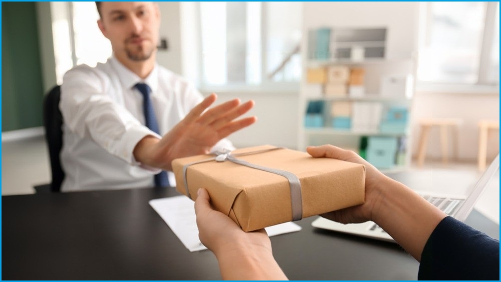 Man in shirt and tie refusing gift being offered to him.