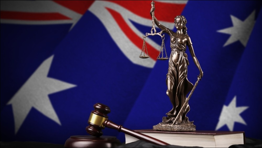 Australian flag with judge's gavel and scales in foreground.