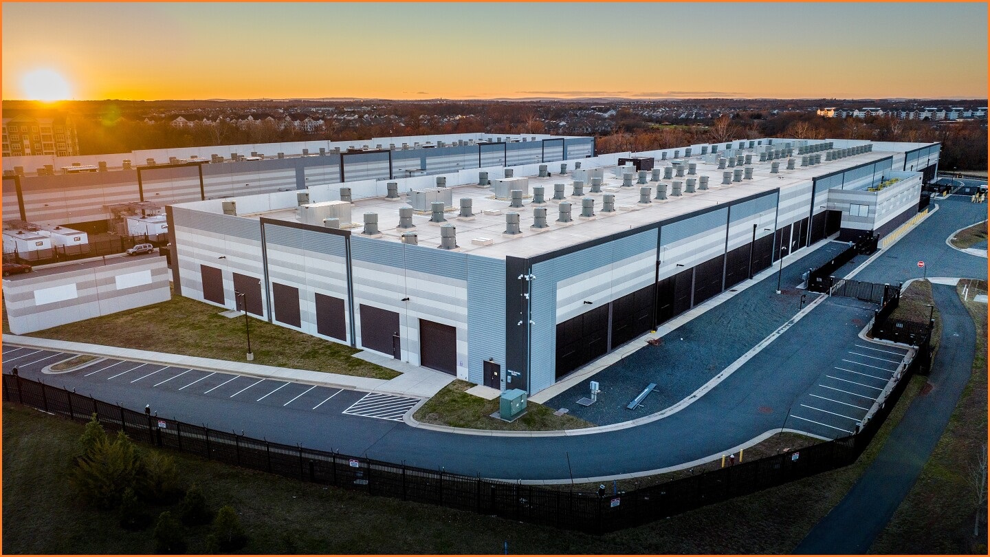 A wide external photo of a large data centre building at sunset.