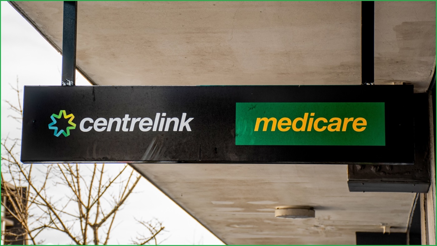 A close up of a sign hanging under an awning displaying the Centrelink and Medicare logos.