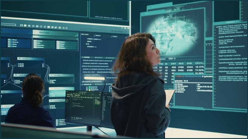 Woman looking at large screens containing data.