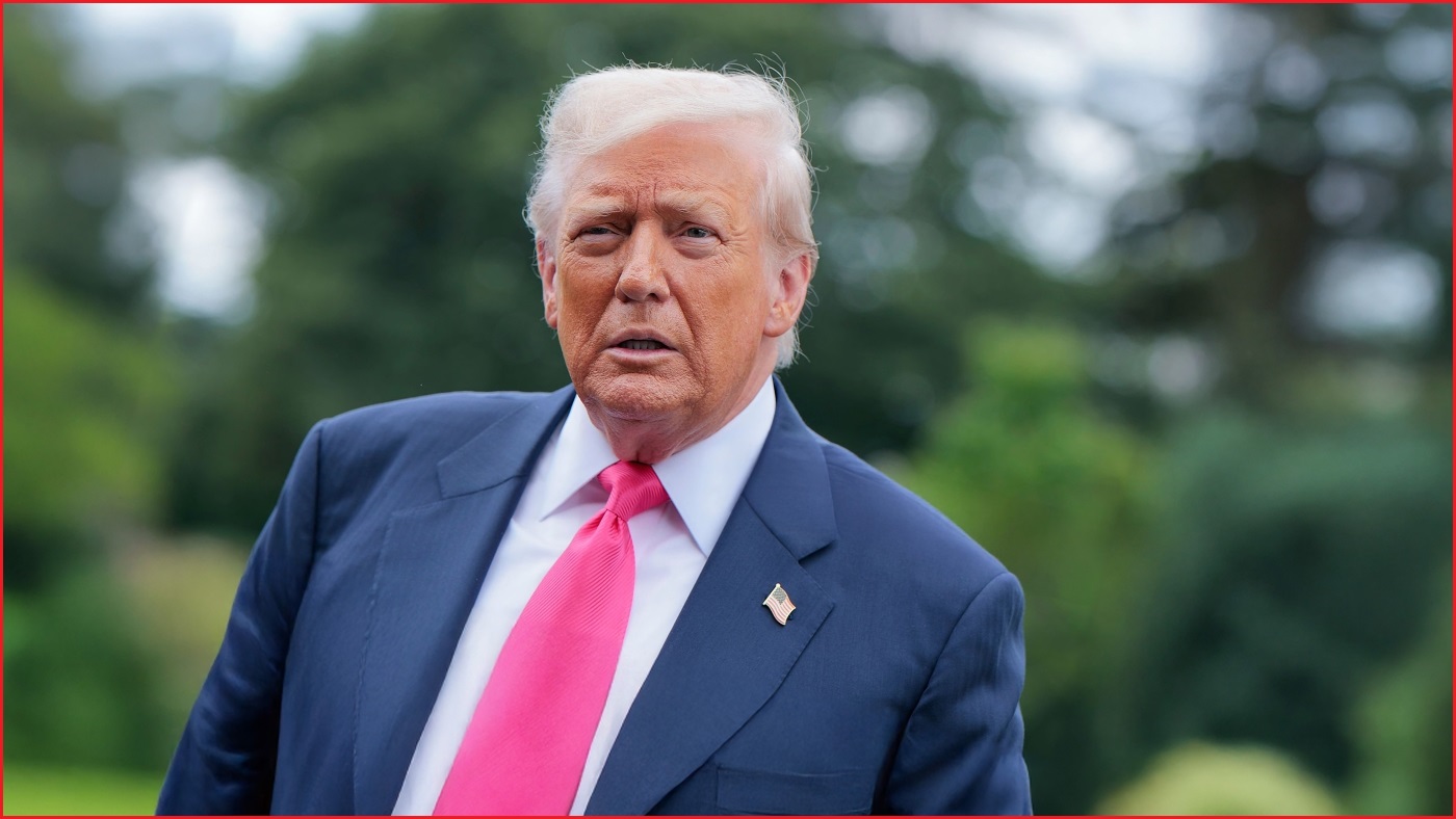 A medium shot of Donald Trump outside, wearing a suit and tie, and looking slightly concerned.
