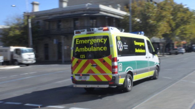 An Australian ambulance racing through an Australian street.