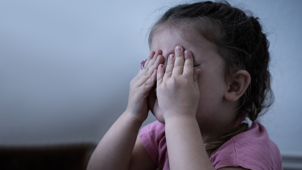 Young girl covering her eyes.