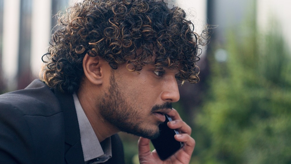 Indian man speakling to someone on the phone.