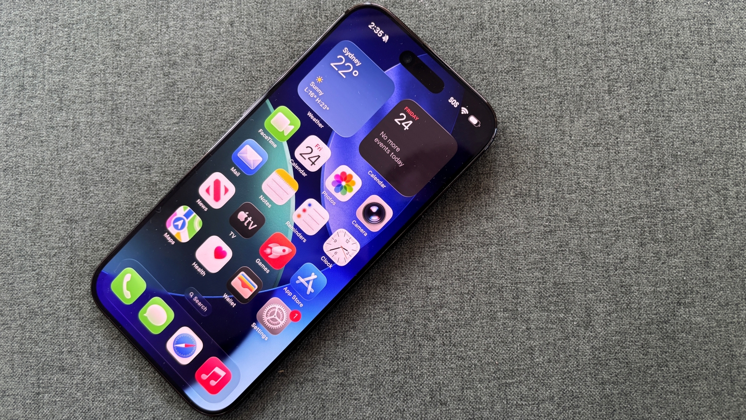 A close up top-down photo of an iPhone Air laying on a fabric surface with its home screen displayed.