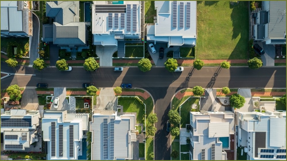 An aerial shot of houses in Sydney showing solar panels on rooftops and pools.