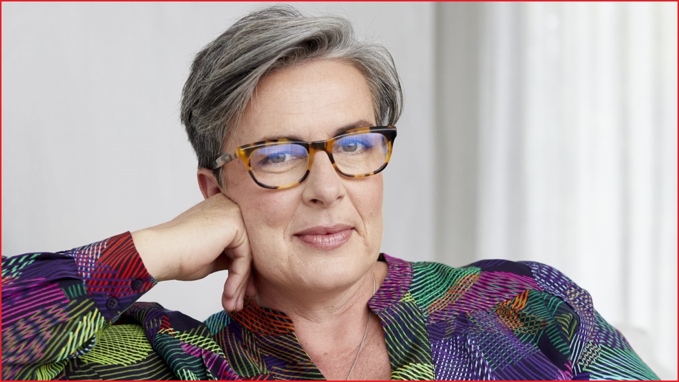 A close up of a middle-aged woman with short-ish hair wearing glasses and smiling slightly.