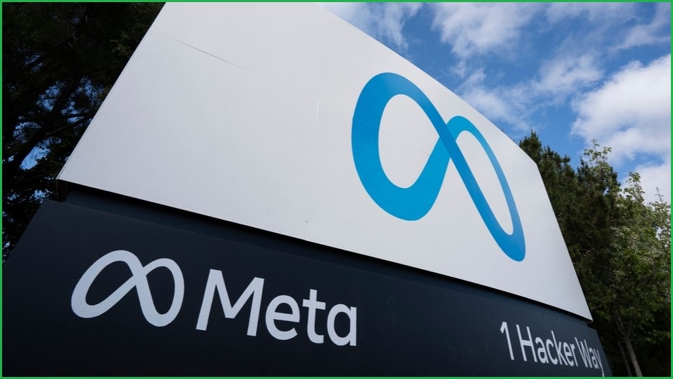 A close up of a sign showing the Meta logo, with trees and sky in the background.