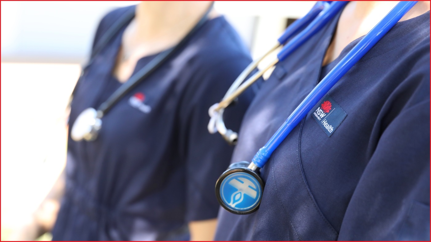 A close up of stethoscopes around the necks of two medical workers, who are wearing NSW Health uniforms.