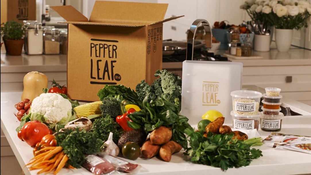 A Pepper Leaf-branded box surrounded by fresh produce on a kitchen counter.