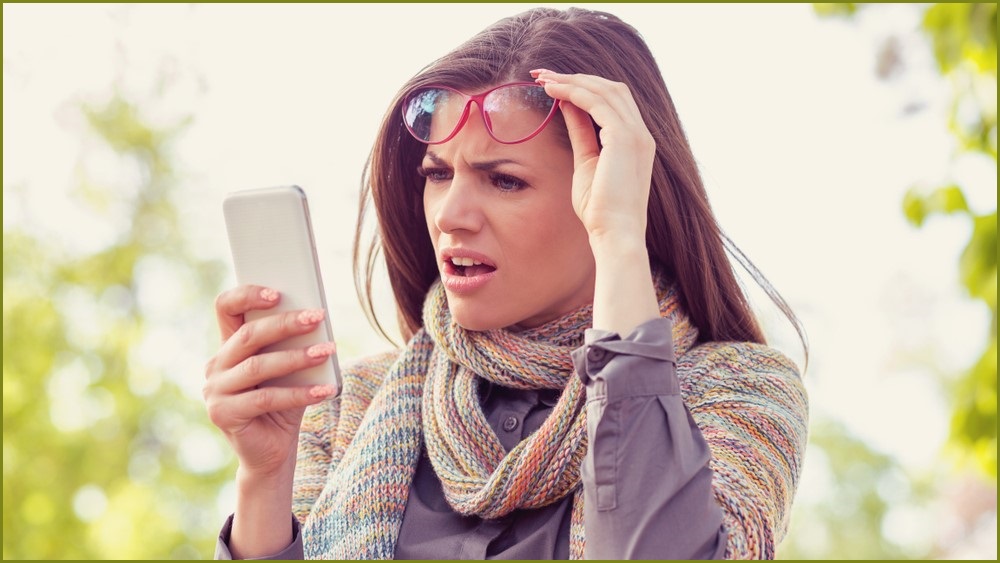 Woman looking at a phone screen with a confused look on her face.