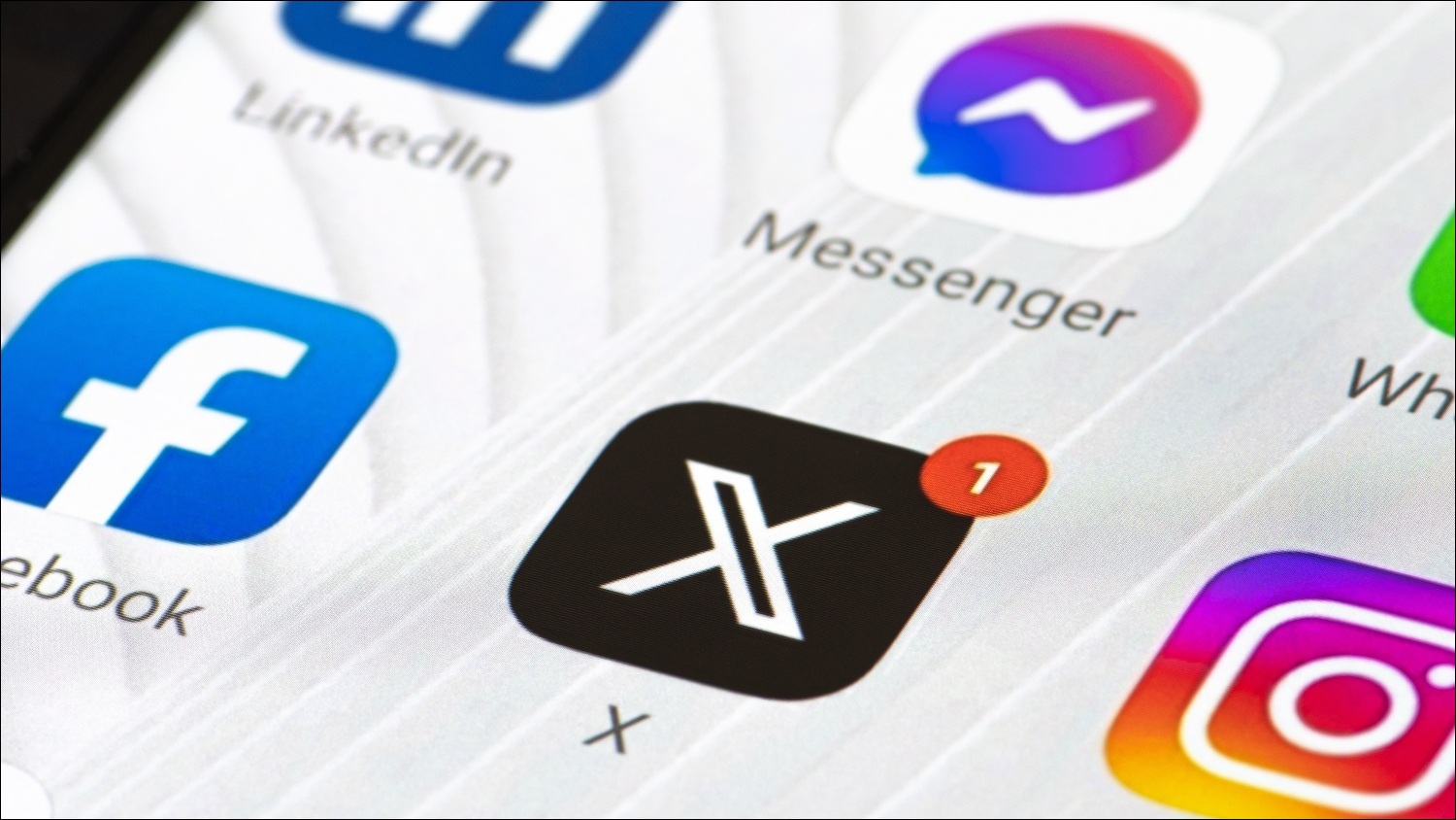 A close up of a smartphone screen displaying apps such as Facebook, X, Messenger, Instagram