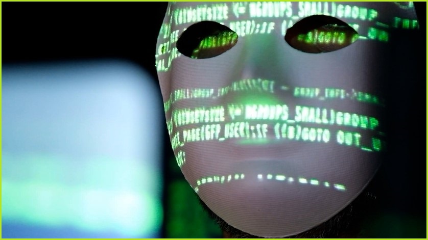 Person wearing white mask with green words and lettering across his face.