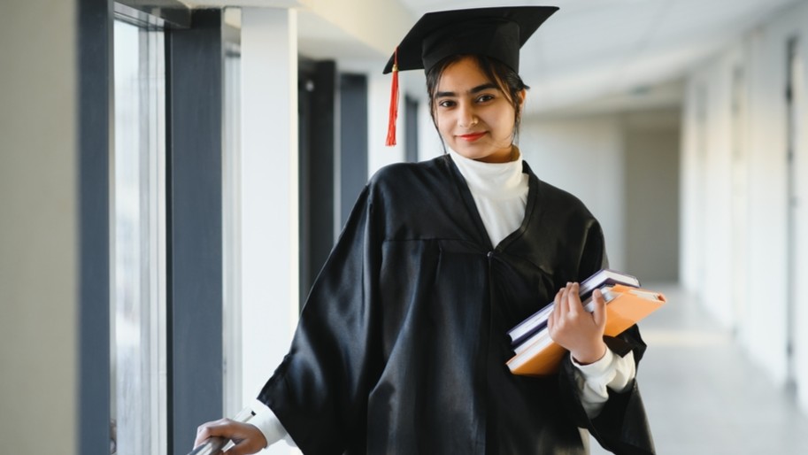 Graduating student hold books.