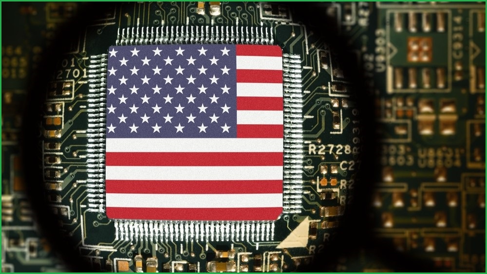 A close up of a computer chip on a motherboard, with the US flag painted across the top of the chip