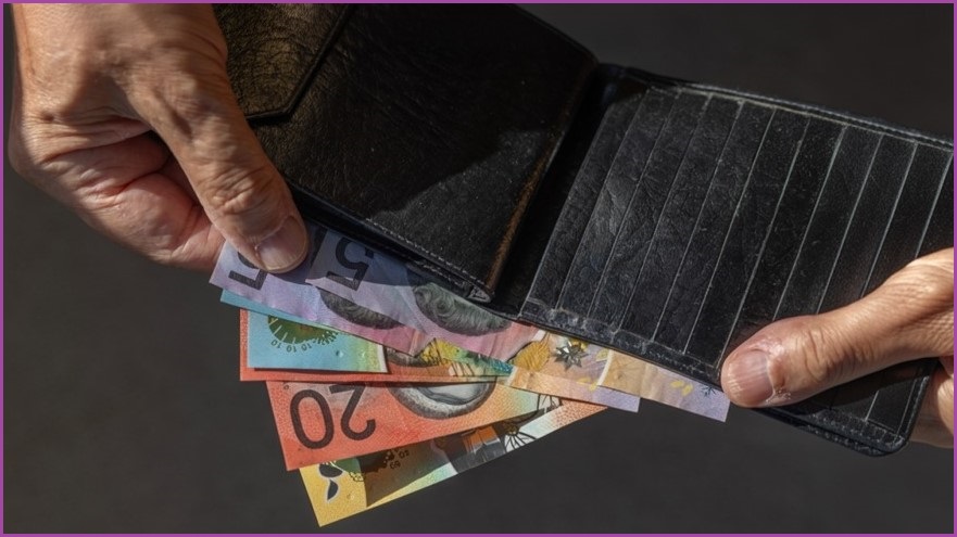 Person holding open wallet showing Australian money inside.