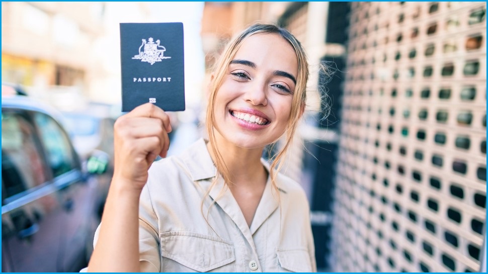 Smiling woman holding up an Australian passport.