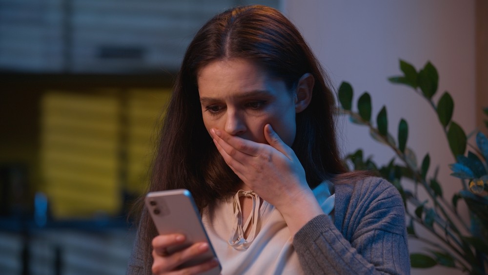 Woman looking at her phone screen in shock.