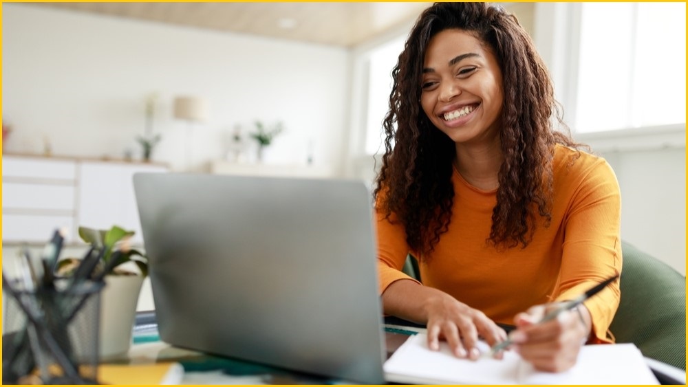 Woman working happily from home on here laptop.
