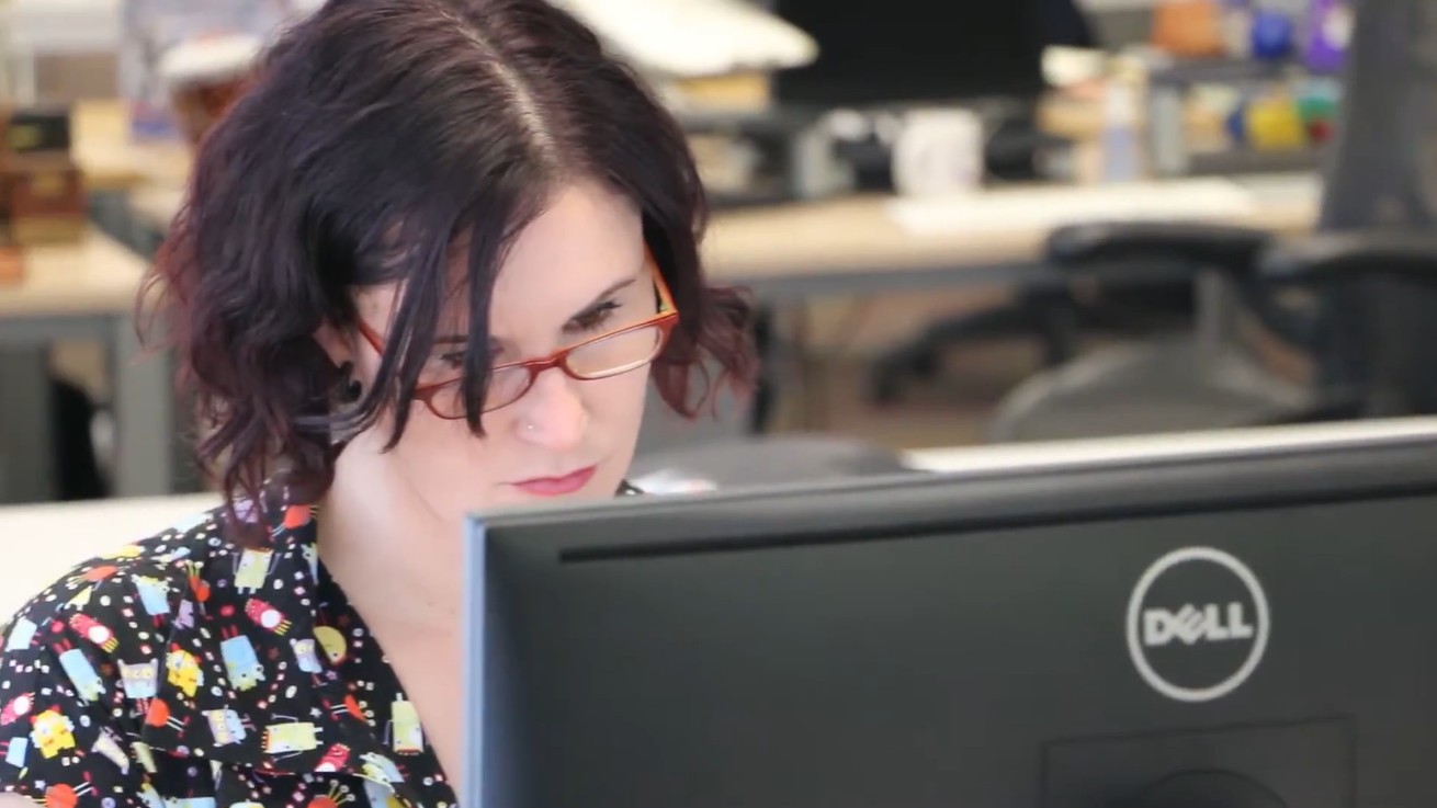 A close up of a woman wearing glasses and working at a computer in an office.