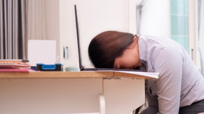 Woman sitting face down with her head on her laptop.