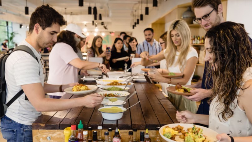 Group of people at a buffet selecting food items.