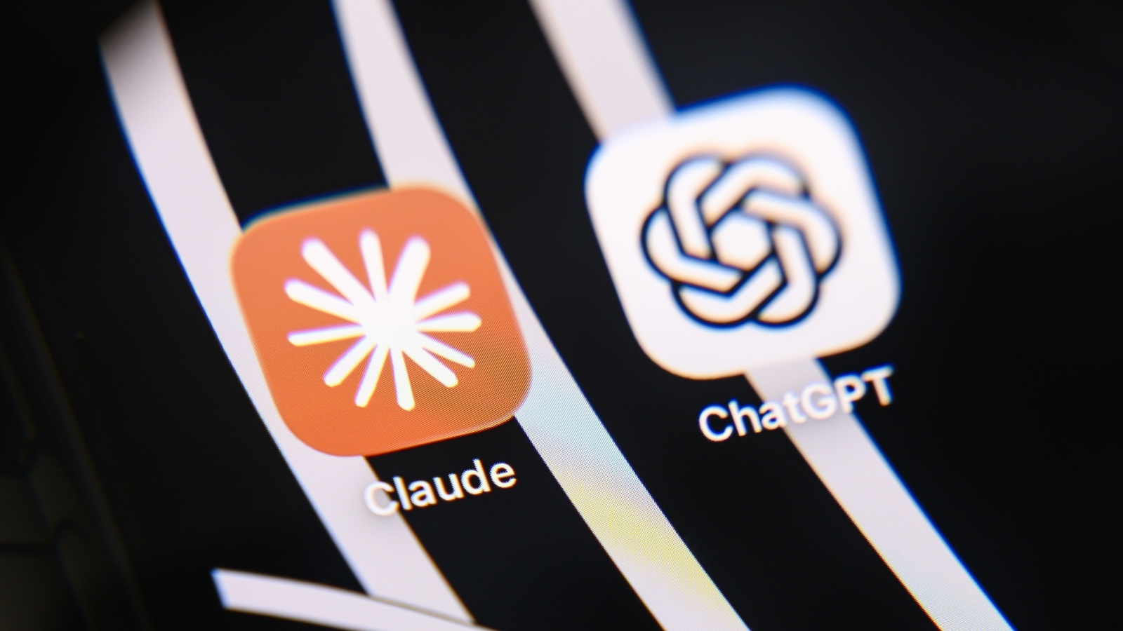 A closeup of a smartphone screen displaying the Claude and ChatGPT app icons.
