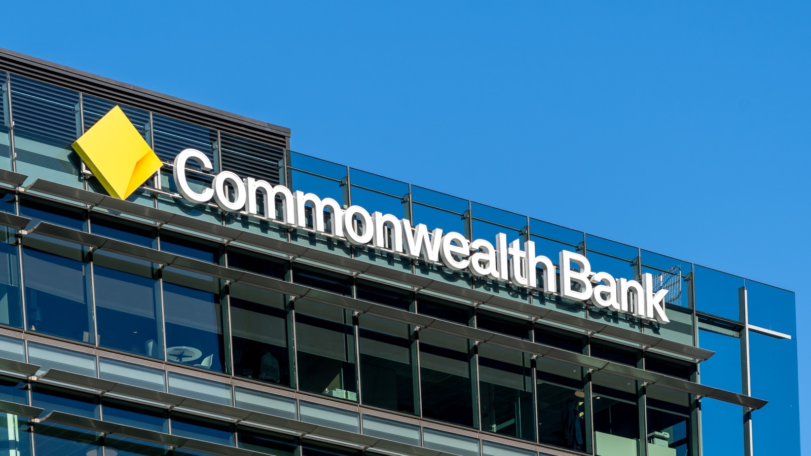 A close up of the Commonwealth Bank logo at the top of a large Commonwealth Bank building.