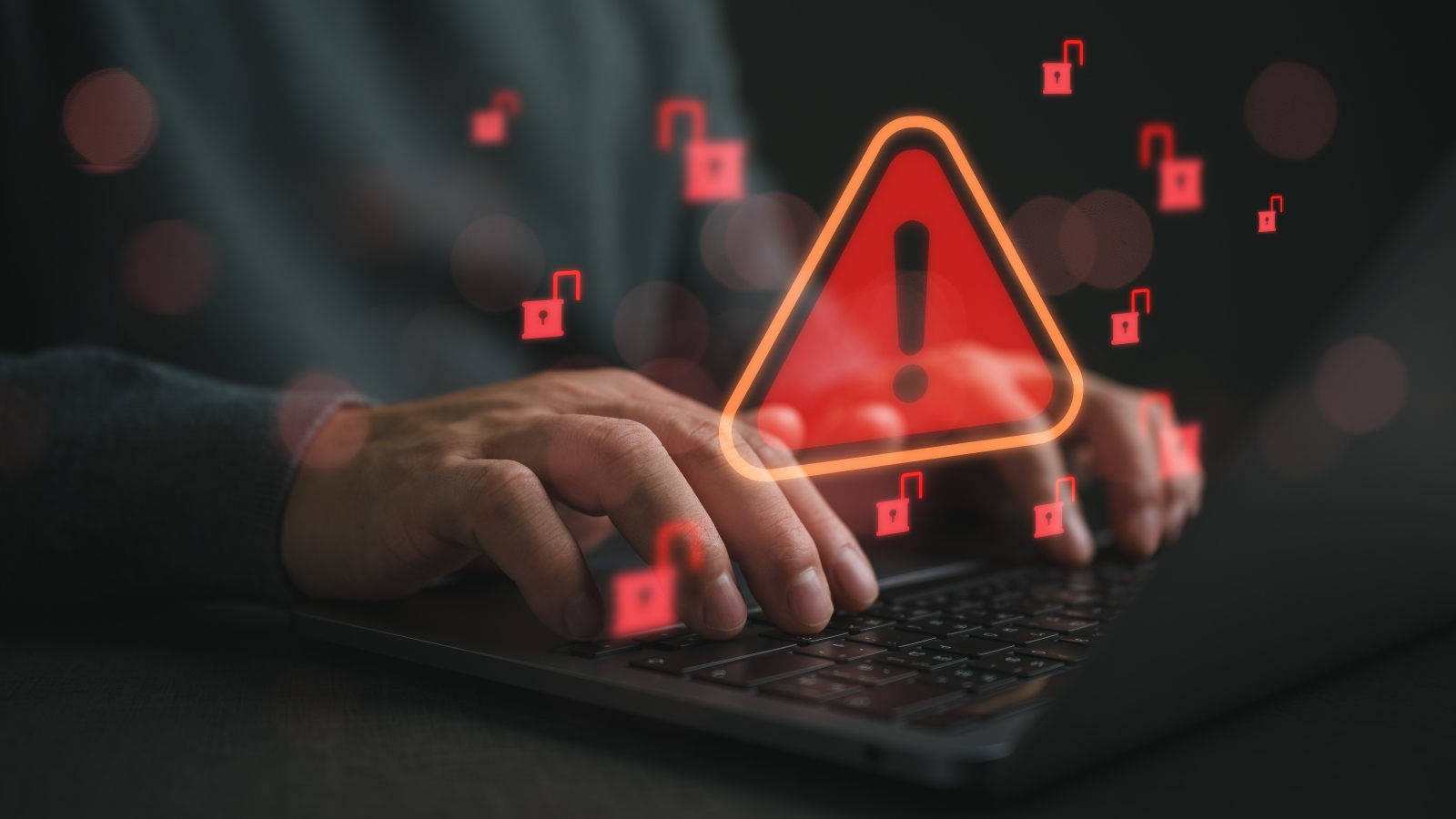 A close up of a man's hands using a laptop keyboard. Images of open locks and a warning sign float in the air.