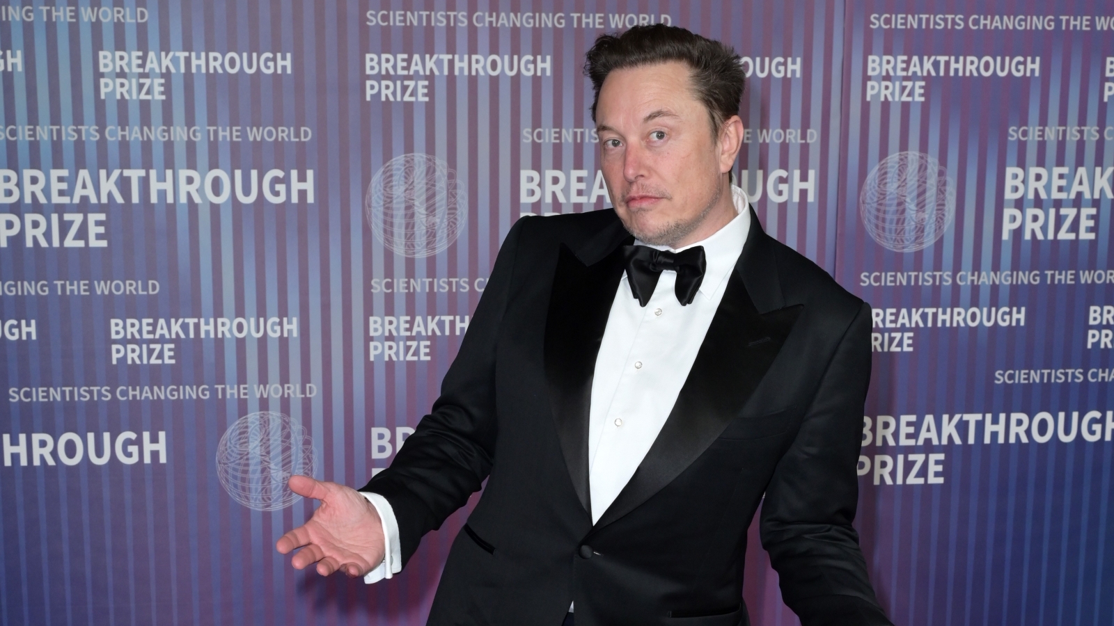 Elon Musk in a tuxedo shrugging.