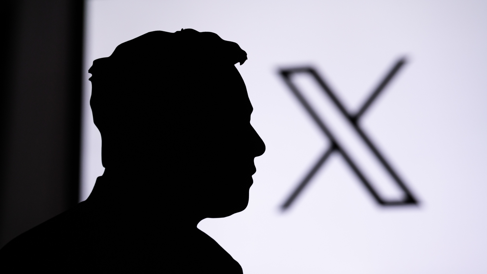 A close up of Elon Musk's shadow, next to the X platform logo.