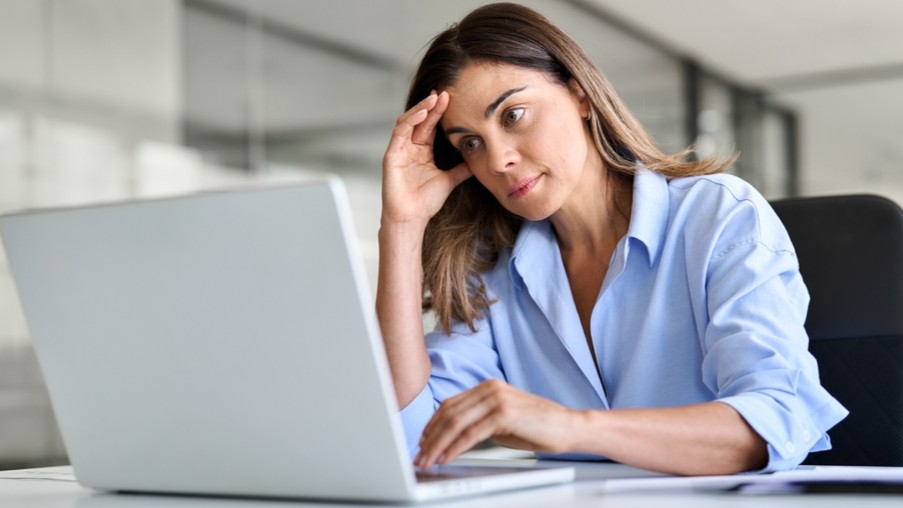 Stressed woman in a blue shirt sitting at a computer/