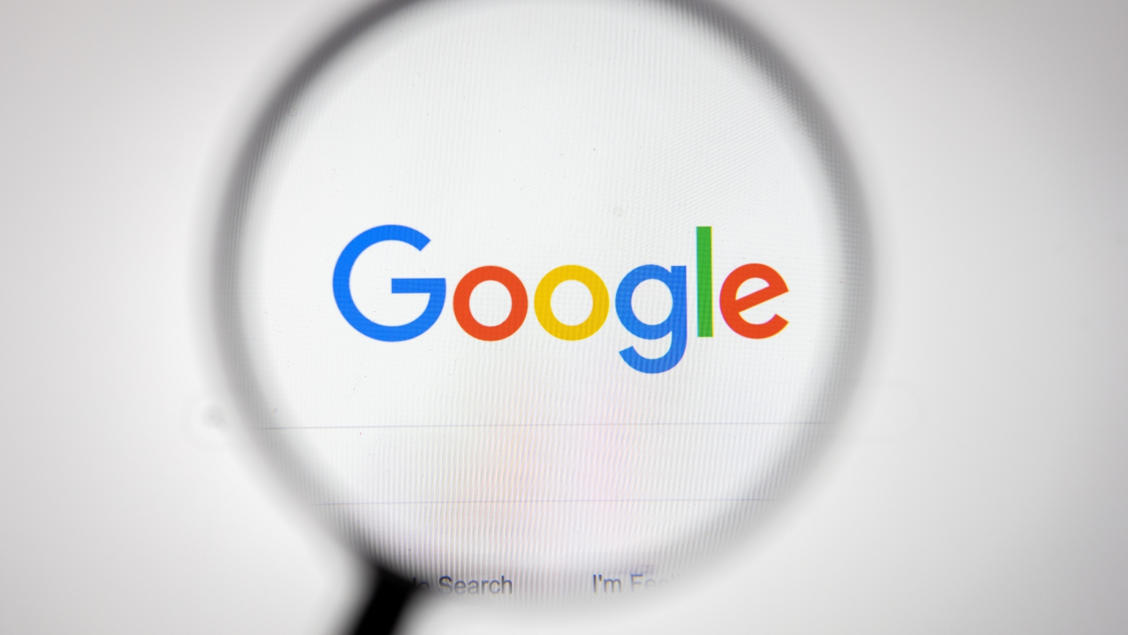 A close up of the Google Search homepage, covered by a large magnifying glass.
