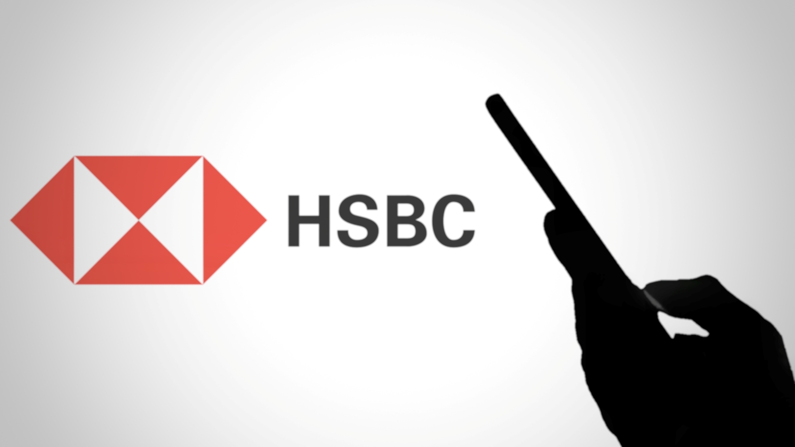 A close up of a person's hand holding a smartphone, next to the HSBC logo.