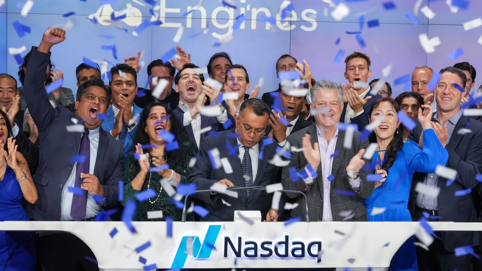 A wide shot of a group of workers celebrating as confetti falls while their company is officially listed on the Nasdaq.